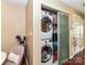 Laundry area features stacked washer and dryer concealed behind sliding doors with shelving for storage at 517 N Graham St # 3E, Charlotte, NC 28202