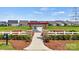 A community garden featuring a white picket fence, red pergola, and garden plots ready for planting against a backdrop of new homes at 527 Sunharvest Ln, Indian Trail, NC 28079