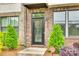 Front entrance featuring a black door, brick facade, and manicured landscaping at 556 Billingsley Rd, Charlotte, NC 28211