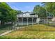 Charming lake house featuring a multi-level deck, lush landscaping, and a secure fenced yard at 592 Shoreline Rd, New London, NC 28127