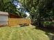 Well-maintained backyard with lush green grass, tall trees, and a wooden fence at 6922 Woodstock Dr, Charlotte, NC 28210