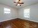 This cozy bedroom features hardwood floors, a ceiling fan, and natural light from the two windows at 6922 Woodstock Dr, Charlotte, NC 28210