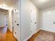 Hallway with hardwood floors, neutral walls, and classic white doors with contrasting dark hardware at 6922 Woodstock Dr, Charlotte, NC 28210