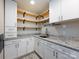Modern laundry room with white cabinets, open wood shelving, and granite countertops at 6922 Woodstock Dr, Charlotte, NC 28210