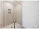 Modern shower featuring light colored tile, glass door, and convenient built-in shelves at 699 Kitfox Nw Dr, Concord, NC 28027