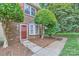 Close-up of home's entrance highlighting the red door, brickwork, and tidy landscaping at 8221 Pineville Matthews Rd # G, Charlotte, NC 28226