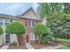 Inviting townhouse featuring brick facade, red shutters, and lush front yard landscaping at 8221 Pineville Matthews Rd # G, Charlotte, NC 28226