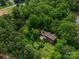 Aerial view of home nestled among trees with expansive lawn and a large deck providing outdoor entertaining space at 104 Ridge Dr, Stanley, NC 28164
