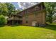 Backyard featuring a brick home with an entertainment deck, lawn, mature trees, and air conditioning units at 104 Ridge Dr, Stanley, NC 28164