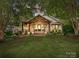 Charming white brick home featuring a covered porch with stylish wood beams and lush landscaping at 1139 Yale Pl, Charlotte, NC 28209