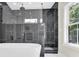 Modern bathroom showcasing a walk-in shower with black marble-style tile and a large soaking tub near a bright window at 124 Starboard Ln, Statesville, NC 28677