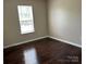 This bedroom features dark wood floors, neutral walls, and a window that provides natural light at 1300 Braveheart Ln, Charlotte, NC 28216