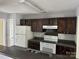 Functional kitchen with dark cabinetry, white appliances, and laminate countertops at 1300 Braveheart Ln, Charlotte, NC 28216