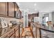 Well-lit kitchen boasts rich cabinetry, granite countertops, stainless steel appliances, and a view of the front door at 17913 Ragtop Day Ln, Cornelius, NC 28031