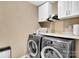 Practical laundry area with modern washer and dryer, storage cabinets, and a functional countertop at 17913 Ragtop Day Ln, Cornelius, NC 28031