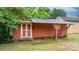 Exterior shot of a rustic shed with a metal roof, white trim doors, and surrounded by lush greenery at 2212 Acme Rd, Belmont, NC 28012