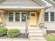 The charming front porch has lovely landscaping and a bright yellow door at 2323 Arden St, Charlotte, NC 28206