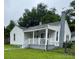 Charming home featuring a covered front porch, white siding, and a painted brick chimney at 247 E Cabarrus Ave, Concord, NC 28025