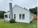 Side view of a single-story home featuring white siding and a grey painted brick chimney at 247 E Cabarrus Ave, Concord, NC 28025