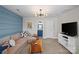 Cozy living room featuring a sectional sofa, blue accent wall, modern chandelier, and an adjacent bathroom at 2863 Grand Union Way, Charlotte, NC 28209