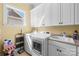 Bright laundry room featuring white cabinetry, washer, dryer, utility sink, and natural light from a window at 458 Inverness Pl, Rock Hill, SC 29730