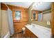 Bathroom featuring log walls, a shower with tub, and a large mirror and vanity at 8464 Robinson Church Rd, Charlotte, NC 28215