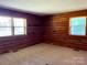 Bedroom with wood paneled walls, carpeted floor, and two windows at 8464 Robinson Church Rd, Charlotte, NC 28215