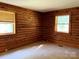 Bedroom with wood paneled walls, carpeted floor, and two windows at 8464 Robinson Church Rd, Charlotte, NC 28215