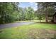 Long gravel driveway leading to a log cabin home surrounded by lush greenery and mature trees at 8464 Robinson Church Rd, Charlotte, NC 28215