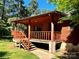 Side view of a log cabin, showing the porch, railings, and stone accents at 8464 Robinson Church Rd, Charlotte, NC 28215