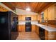 Functional kitchen featuring wood cabinets, black appliances, and wood-look floors in a log cabin home at 8464 Robinson Church Rd, Charlotte, NC 28215