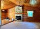 Cozy living room featuring wood paneled walls, a stone fireplace, and a ceiling fan at 8464 Robinson Church Rd, Charlotte, NC 28215