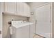 Laundry room featuring white washer and dryer, cabinets, and exterior door at 9217 Tenby Ln, Matthews, NC 28104