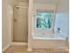 Bathroom featuring a tub with a shower, shower doors, and large window at 9907 Furlong Trl, Charlotte, NC 28269