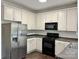 Kitchen features white cabinets, black appliances, and a stainless-steel refrigerator at 9907 Furlong Trl, Charlotte, NC 28269