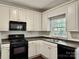 Well-lit kitchen featuring white cabinets, black appliances, and a window over the stainless steel sink at 9907 Furlong Trl, Charlotte, NC 28269