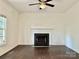 A spacious living room with a fireplace, fan, and dark hardwood floors at 9907 Furlong Trl, Charlotte, NC 28269