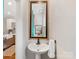 Bathroom featuring a pedestal sink, decorative mirror, and a glimpse of the modern kitchen at 100 N Laurel Ave # 107, Charlotte, NC 28207