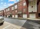 Exterior view of brick townhomes, highlighting garage doors, windows, and street parking at 100 N Laurel Ave # 107, Charlotte, NC 28207