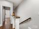 Bright hallway with hardwood floors, white trim, and staircase with wooden handrail and modern lighting fixture at 100 N Laurel Ave # 107, Charlotte, NC 28207