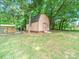 Well-maintained backyard featuring a storage shed surrounded by mature trees on a sunny day at 1021 Mallard Landing Dr, Monroe, NC 28110