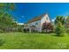 Large backyard with expansive lawn and lush trees surrounding a two-story home with sunroom addition at 10418 Goosefoot Nw Ct, Concord, NC 28027