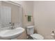 Cozy powder room featuring a pedestal sink, mirror, and toilet with neutral wall color at 10418 Goosefoot Nw Ct, Concord, NC 28027
