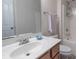 Bright bathroom featuring a white single sink vanity, large mirror, and tiled shower with convenient storage at 10418 Goosefoot Nw Ct, Concord, NC 28027