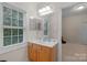 Well-lit bathroom featuring a wooden vanity, a large mirror, and a bright window with views to the outside at 10418 Goosefoot Nw Ct, Concord, NC 28027