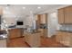 Bright open kitchen with stainless steel appliances, center island, wooden cabinets, granite countertops and hardwood floors at 10418 Goosefoot Nw Ct, Concord, NC 28027