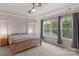 Serene primary bedroom with tray ceiling, natural light from windows, and a wooden bed frame at 10418 Goosefoot Nw Ct, Concord, NC 28027