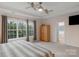 Primary bedroom with natural light from windows, neutral colored walls, and a wooden armoire at 10418 Goosefoot Nw Ct, Concord, NC 28027