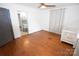 Bedroom with hardwood floors, a ceiling fan, neutral curtains, and a gray door leading to the bathroom at 1101 Pee Dee Ave, Albemarle, NC 28001