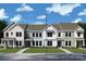 New construction townhomes featuring varied color schemes, covered porches, and professional landscaping at 11455 Prosperity Church Rd, Huntersville, NC 28078